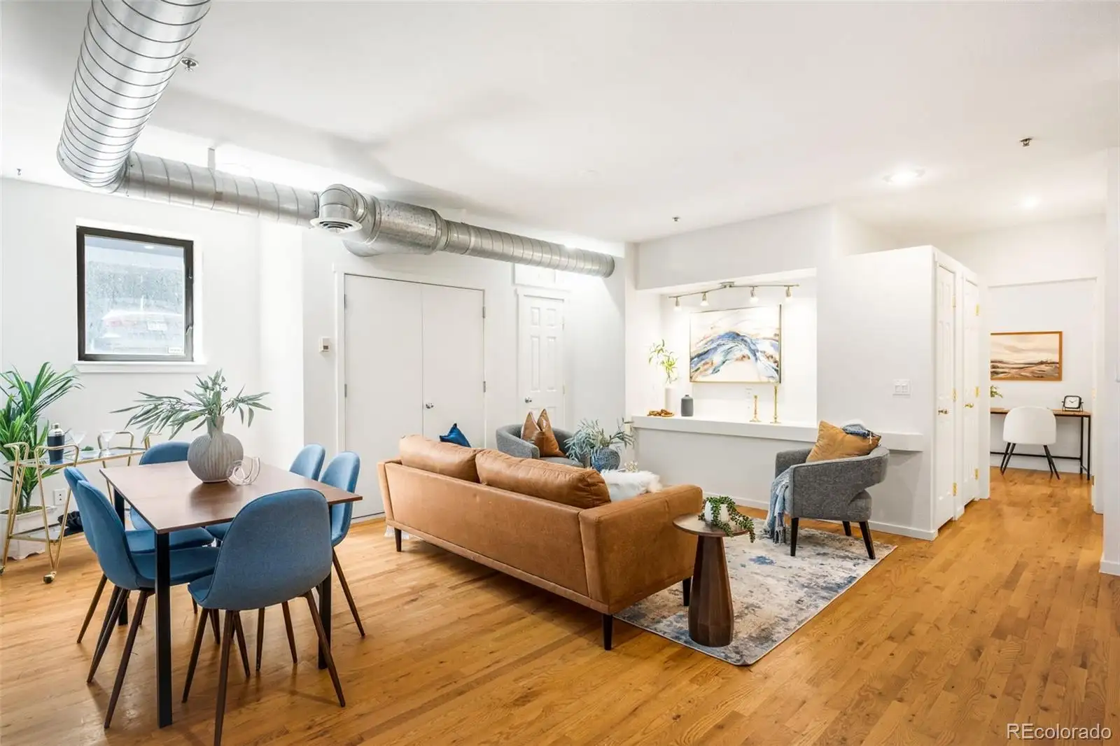 Open living and dining area with exposed ductwork and hardwood floors