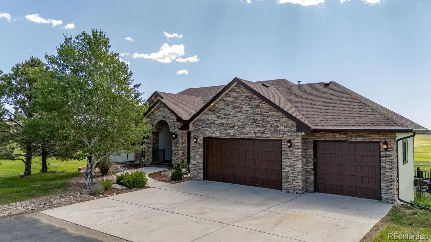 Front exterior with a stone-and-stucco facade and three-car garage