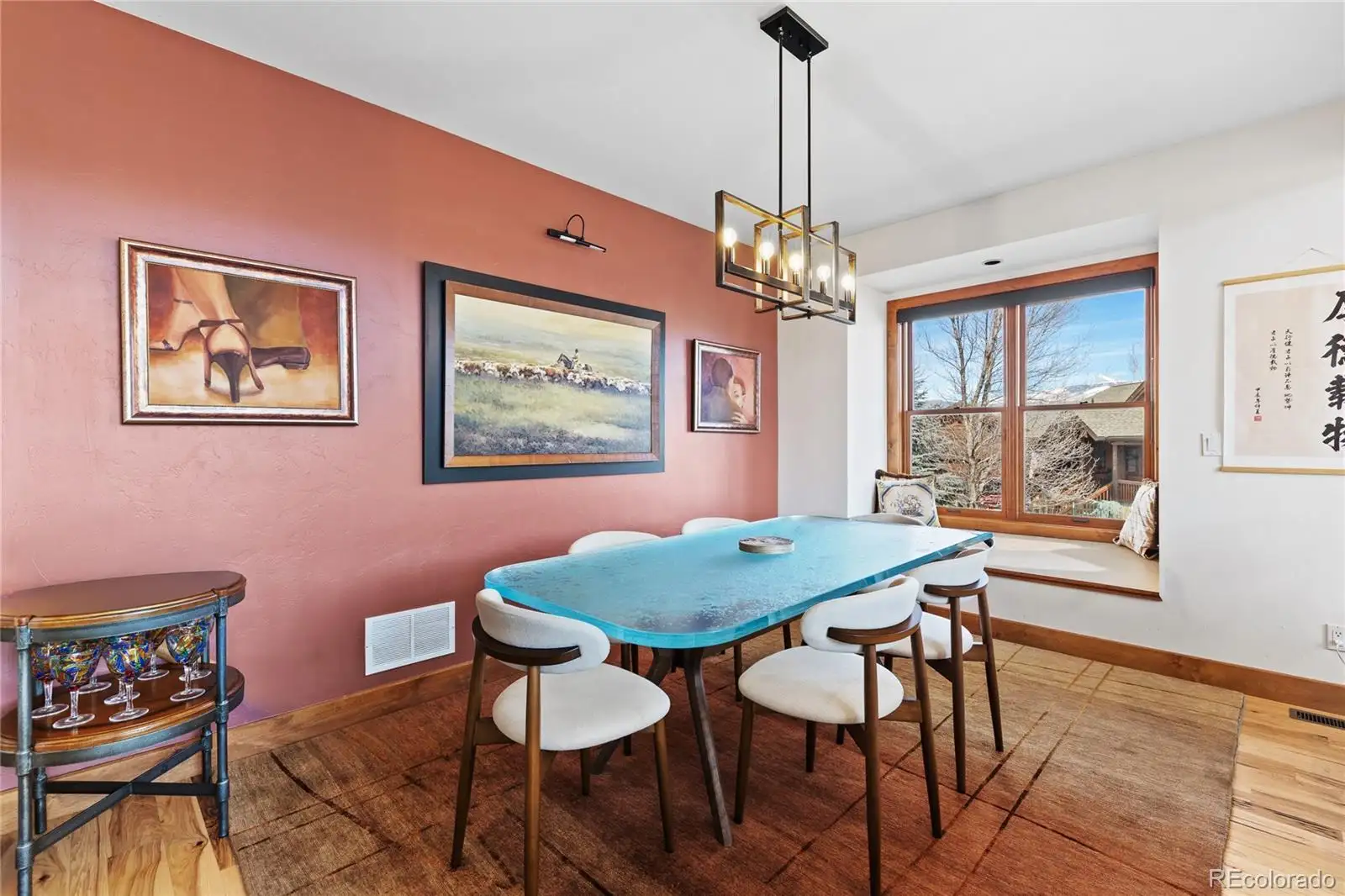 Dining area with a blue table, pendant lighting and terracotta walls