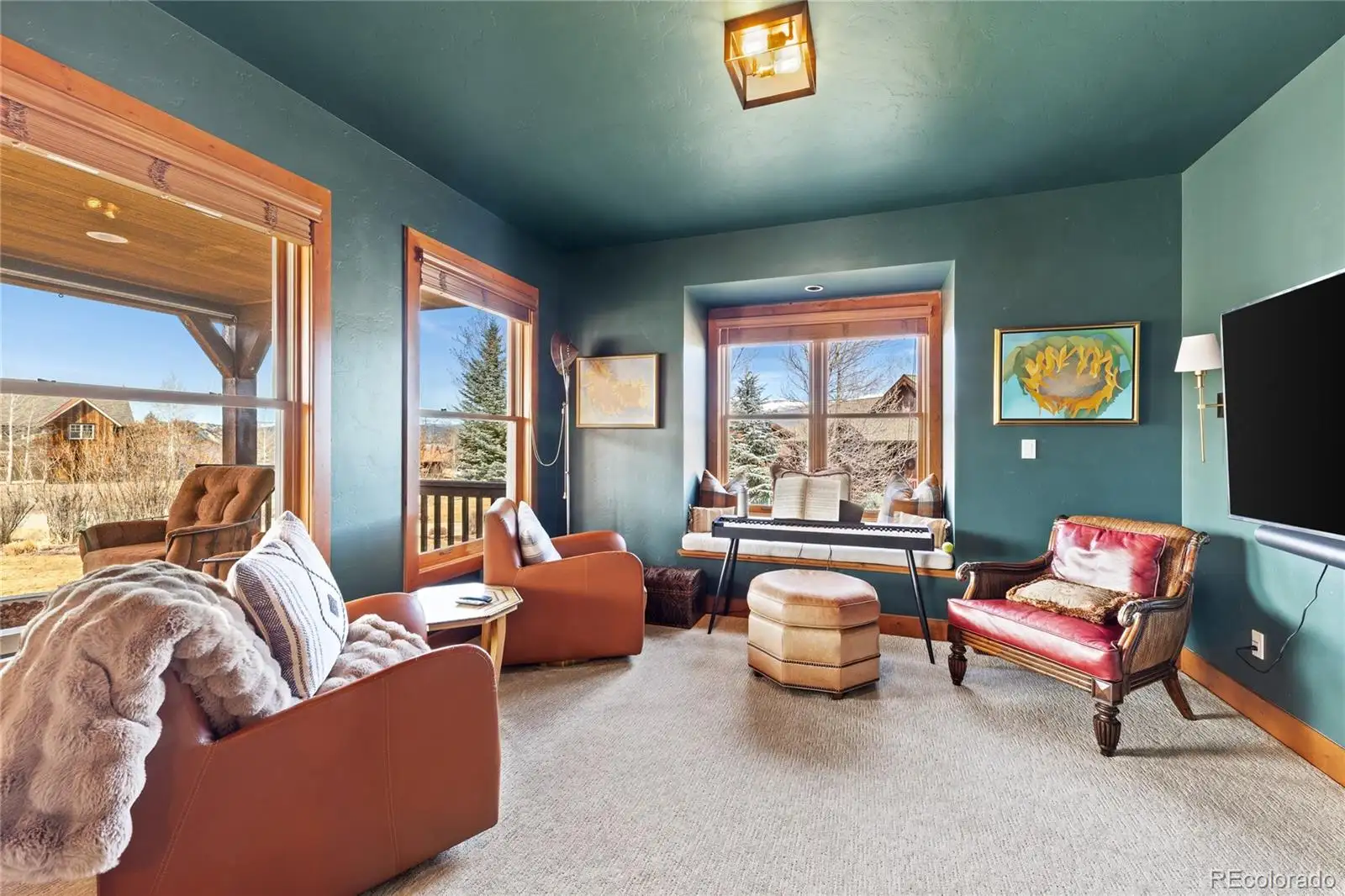 Den with deep green walls and windows toward the golf course