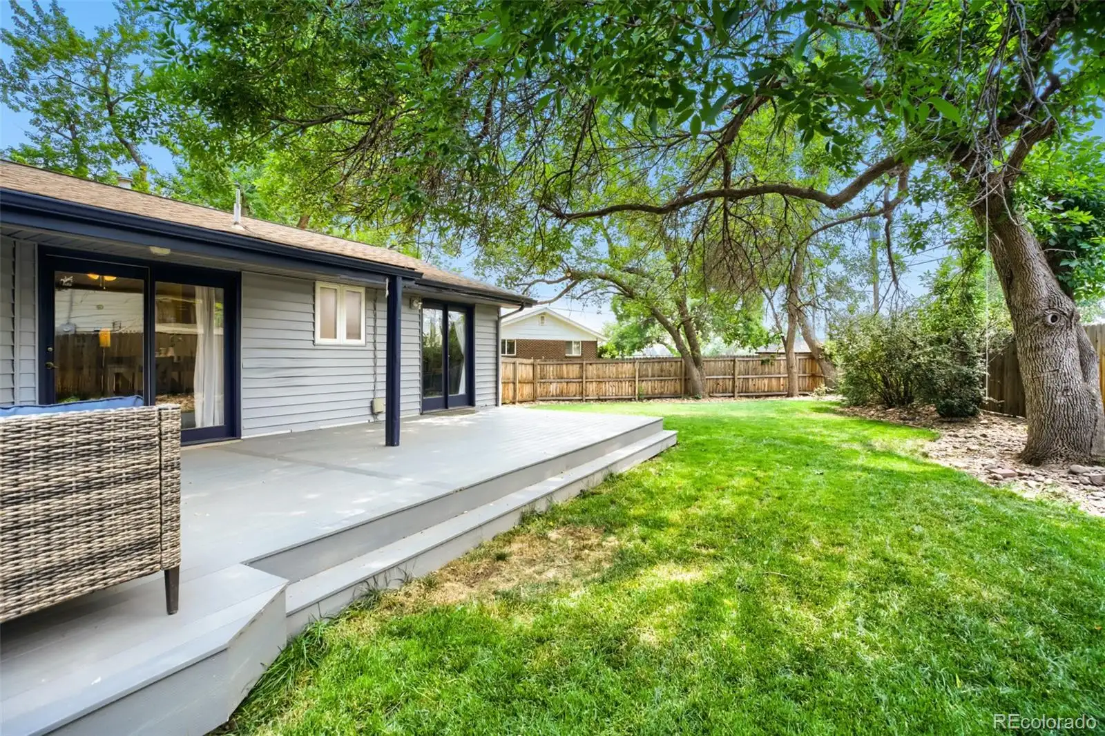 Covered patio and deep backyard beneath mature trees at 5125 Zinnia Court