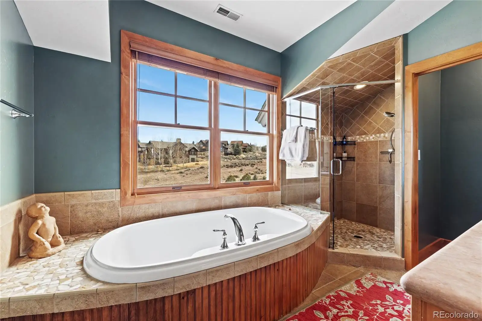 Primary bath with a soaking tub beneath the window and a walk-in shower
