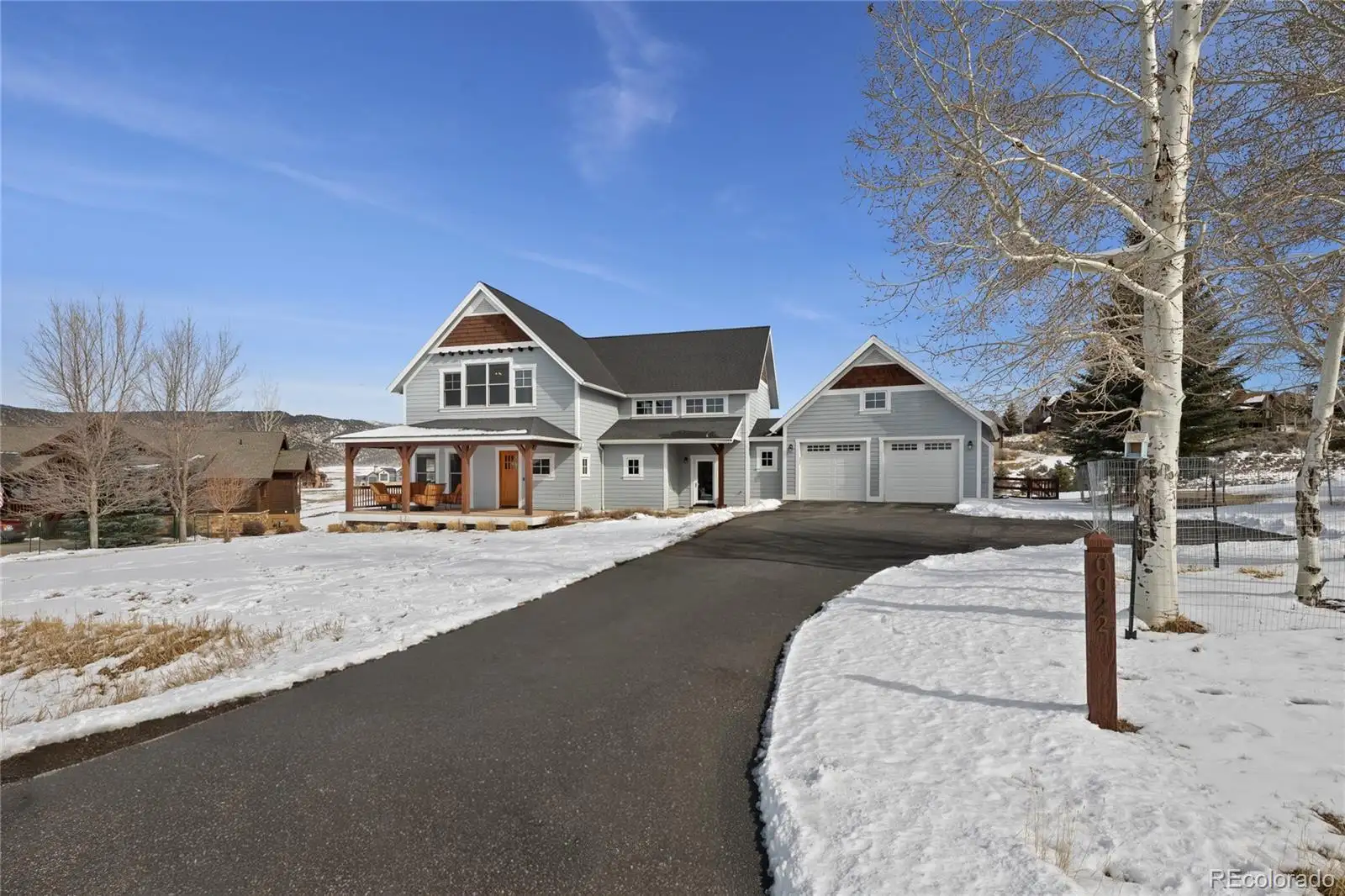 Driveway approach in winter, with the home and garage beyond