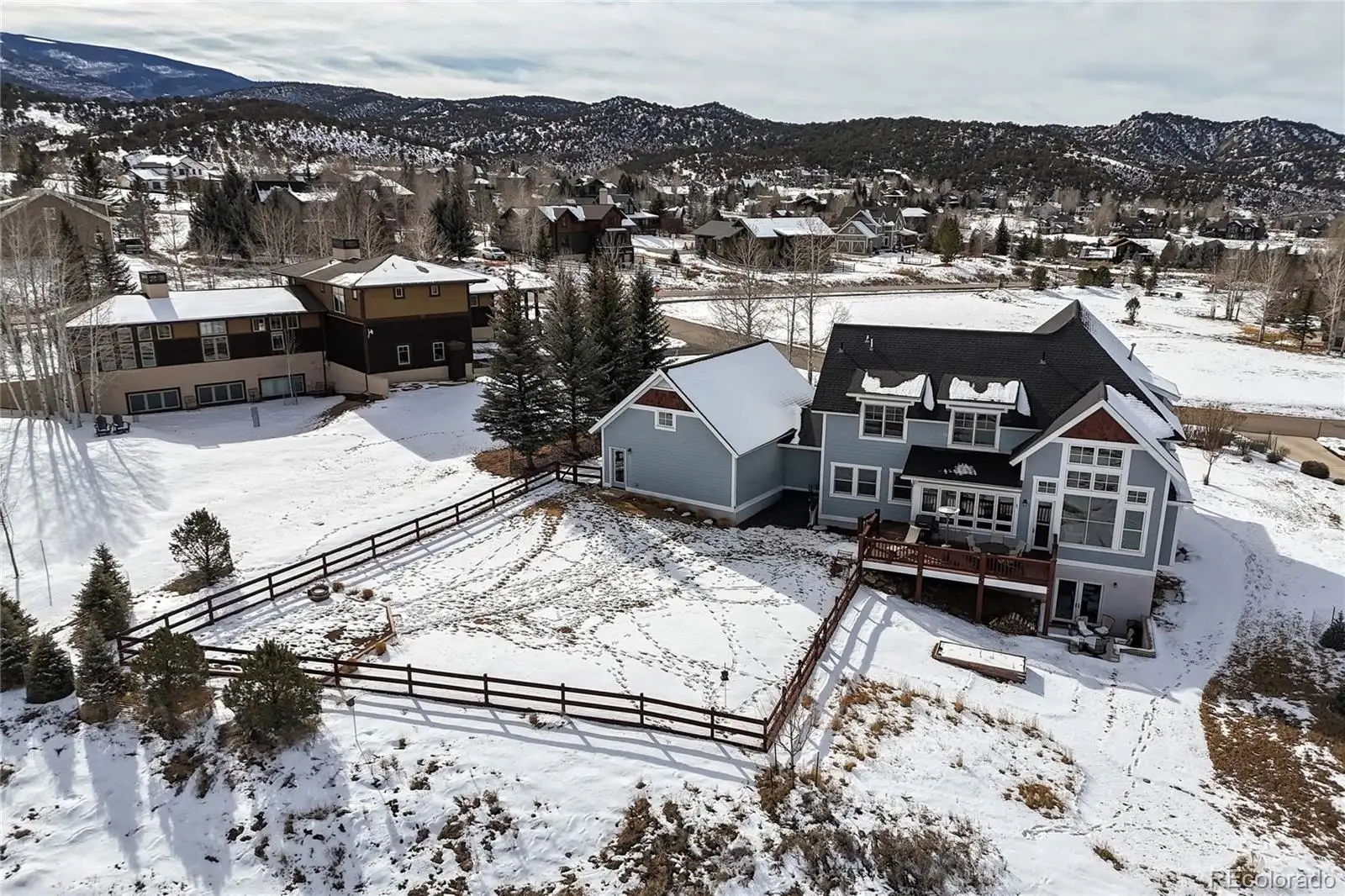 Aerial view of the home and fenced yard beside Eagle Ranch Golf Course, under snow