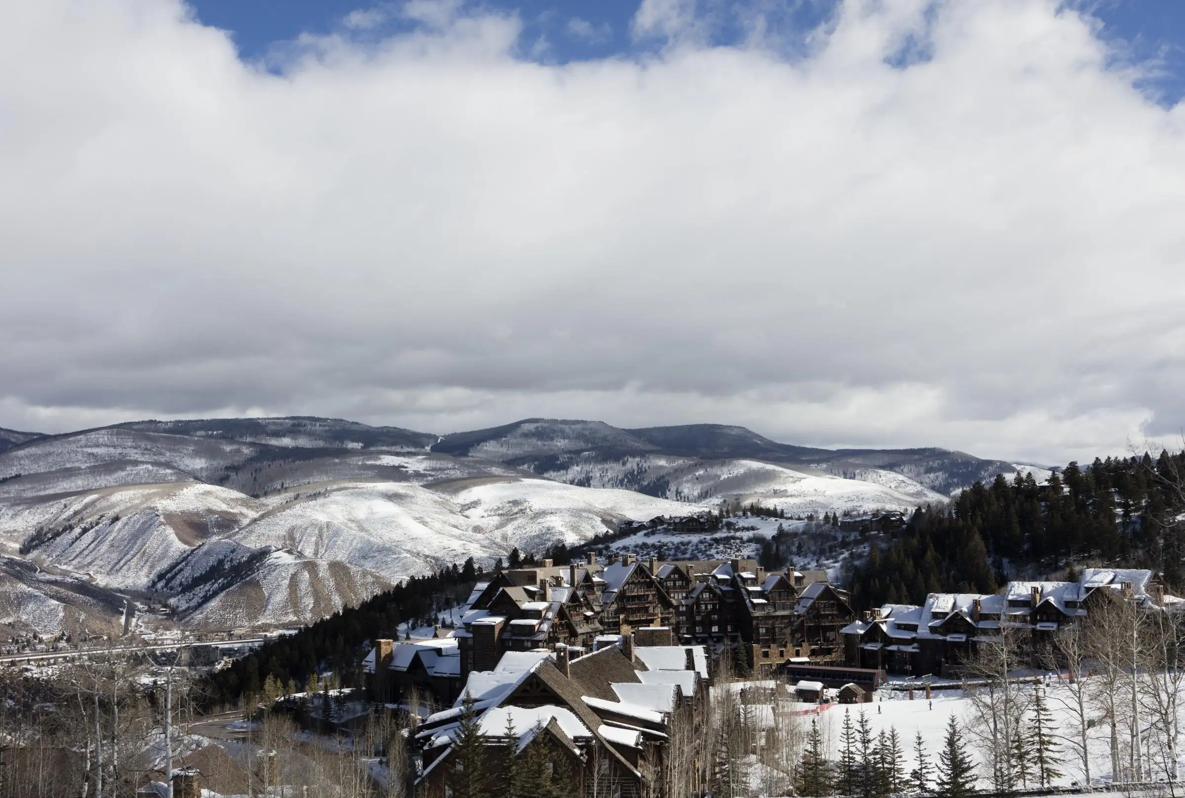 Lodges and homes among snow-covered aspens at Bachelor Gulch, with the valley beyond