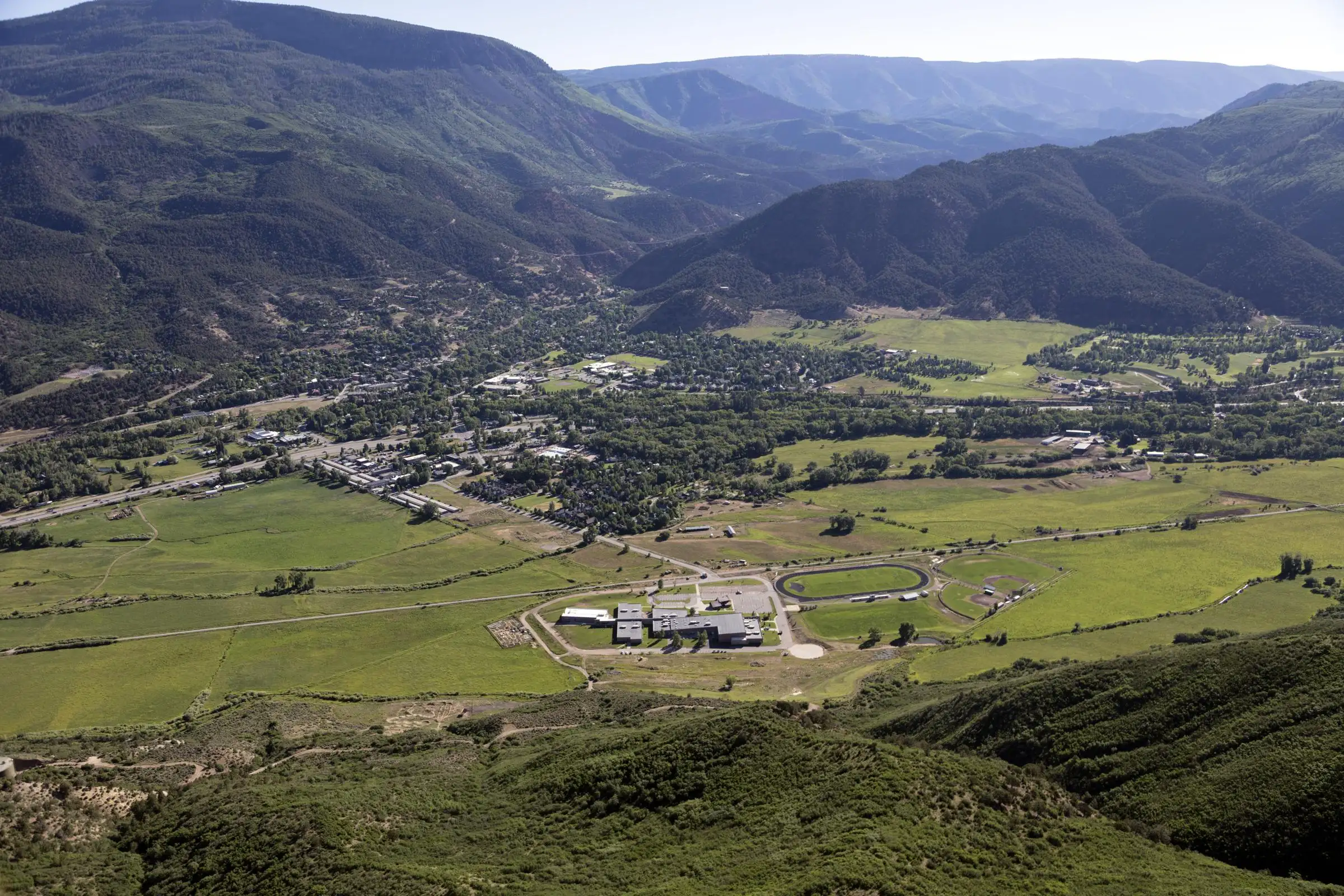 Aerial view of a green valley floor and forested ridges in Eagle County