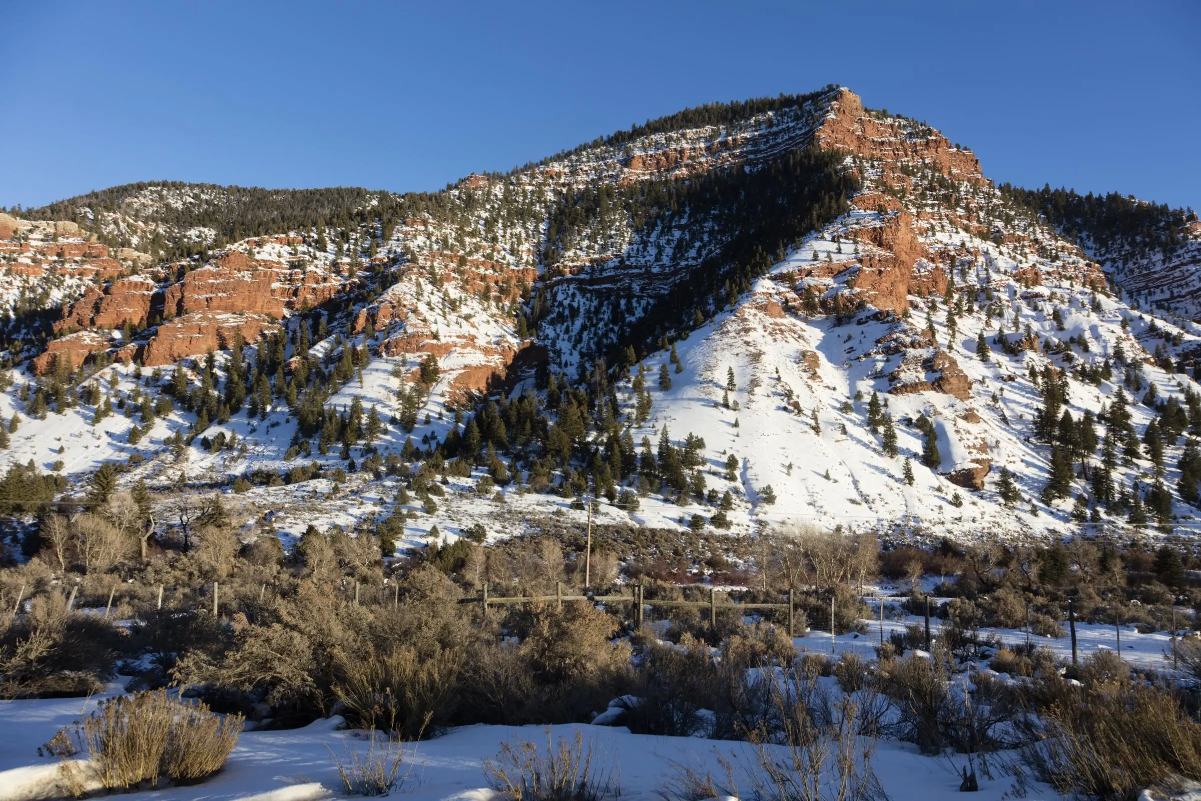 A red sandstone hillside dusted with snow near Wolcott